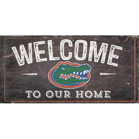 Vintage-style "University of Florida welcome" sign featuring a colorful alligator illustration on a distressed wooden background.