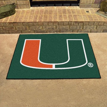 A University of Miami Hurricanes All Star Mat with a green background and the orange and white "u" symbol, placed on a textured beige surface.