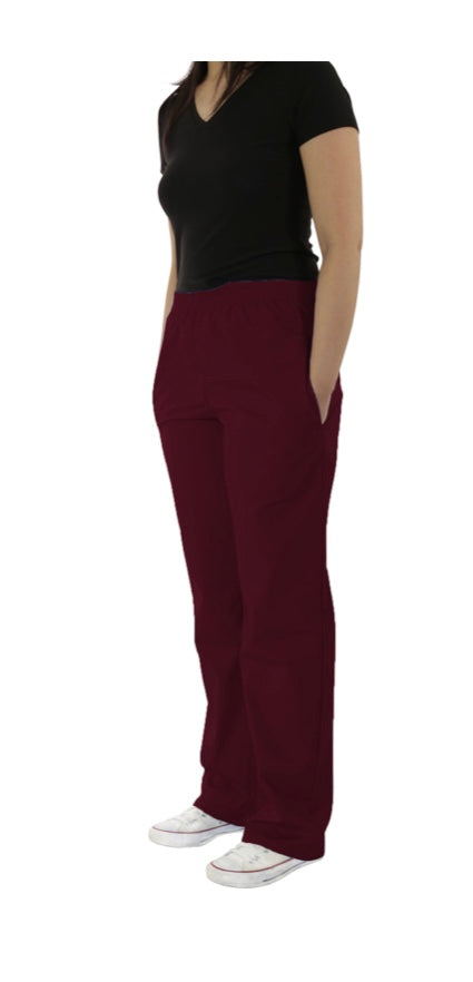 Woman standing in a side pose wearing a black top, the UltraSoft Unisex Classic Elastic Waist Scrub Pants 300C, and white sneakers.