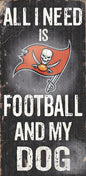 Sign with the text "all i need is football and my dog" featuring a tampa bay buccaneers logo, displayed on a worn, wooden background.