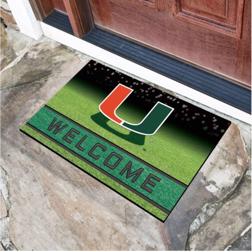 A Miami Hurricanes Crumb Rubber Door Mat featuring the University of Miami logo with a green background and the word "welcome" at a house entrance.