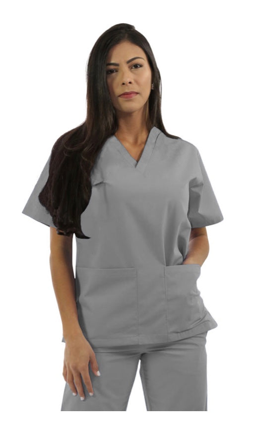 A woman in gray scrubs stands against a white background, looking directly at the camera with a neutral expression.