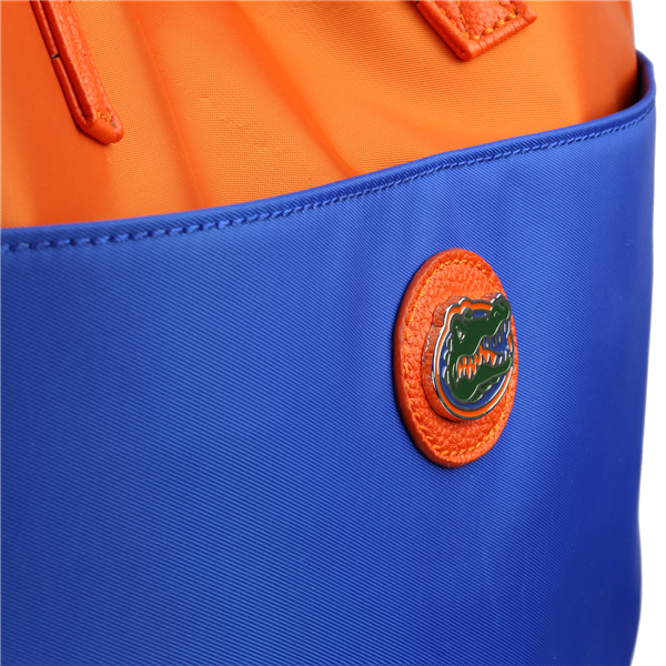 Close-up of a bright orange and blue bag with a round The Phyllis Handbag (University of Florida Gators) logo badge attached to it.