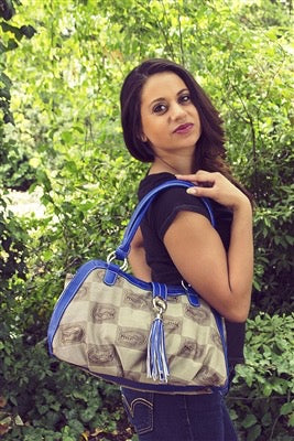 A woman with dark hair posing in a lush garden, holding The Patriot Handbag (Florida Gators) over her shoulder.