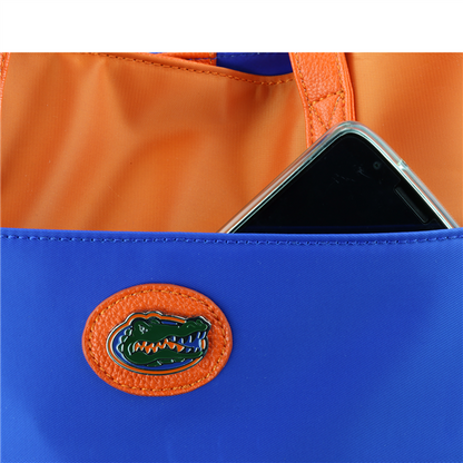 Smartphone partially inserted in a blue and orange The Phyllis Handbag (University of Florida Gators).