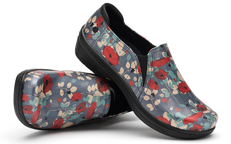 A pair of Moxy by Klogs Footwear slip-on shoes with red poppies and blue background, positioned against a white backdrop.