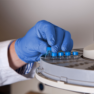 A AMMEX Professional Cerulean Nitrile PF Exam Gloves placing vials into a laboratory centrifuge.