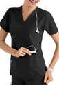 A smiling healthcare professional in a CROSS FLEX V-NECK MEDIA SCRUB TOP C12110 with a stethoscope around her neck, inserting a device into her pocket.