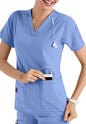 A smiling healthcare professional in CROSS FLEX V-NECK MEDIA SCRUB TOP C12110 placing a mobile device into her pocket.