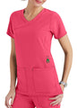 Woman in pink medical scrubs with a v-neck and large pockets, posing with her hand on her hip.
