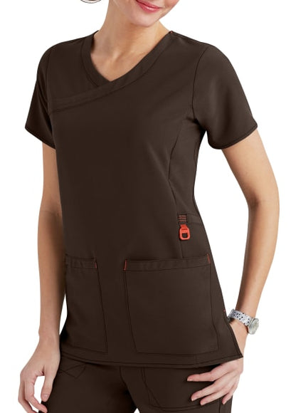 A woman wearing a stylish brown scrub top with multiple pockets, featuring orange accents. she is partially visible with a focus on the scrub top.