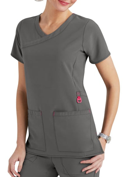 A woman wearing a gray nursing scrubs top with pockets, featuring red accents and a v-neck design.