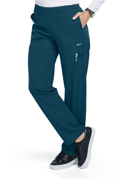 A person wearing teal medical scrub FLAT FRONT STRAIGHT LEG PANT C52106 and black sneakers, with a hand resting on the hip and the focus on the pants pocket details.