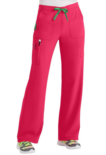 Bright pink CROSS FLEX UTILITY BOOT CUT SCRUB PANT C52110 with green drawstring, multiple pockets, and visible footwear in lime and black sneakers.
