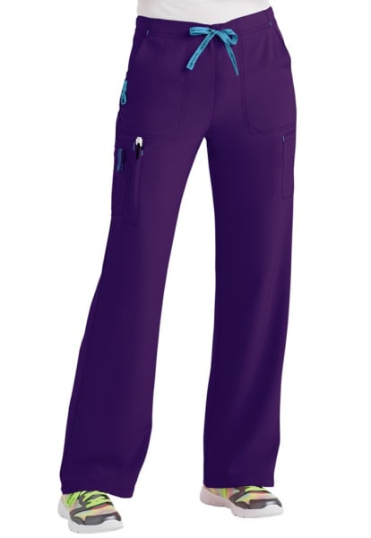 A pair of CROSS FLEX UTILITY BOOT CUT SCRUB PANT C52110 with a blue drawstring, multiple pockets, and partially visible sneakers with colorful accents.