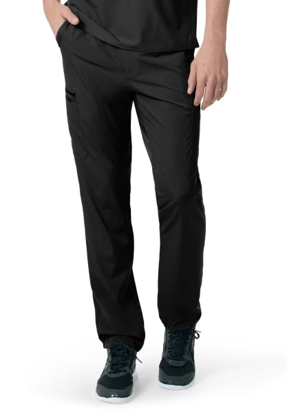 Close-up of black CARHARTT C55106 - MEN'S ATHLETIC CARGO PANT and teal sneakers worn by a person standing with one hand partially tucked in a pocket.